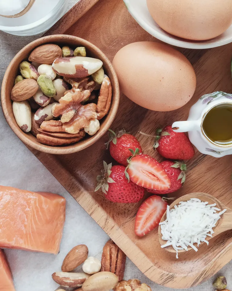 A spread of salmon, eggs, strawberries, mixed nuts and coconut on a wooden board
