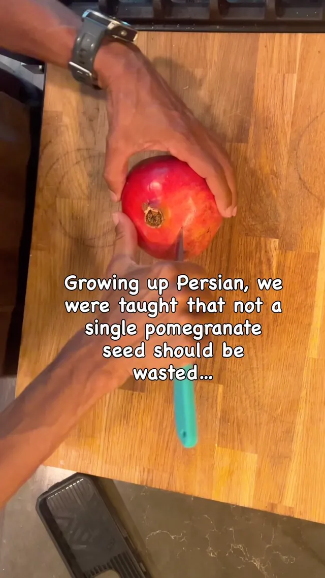 Hands holding a pomegranate over a wooden chopping board
