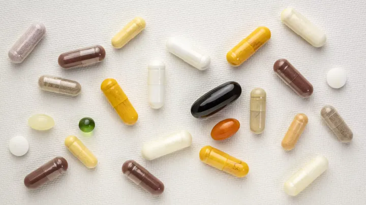 Assorted supplement capsules scattered on a pale surface